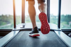 Male feet in sneakers running on the treadmill at the gym. Exerc