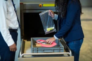 Mid section of commuter collecting accessories from crate in airport